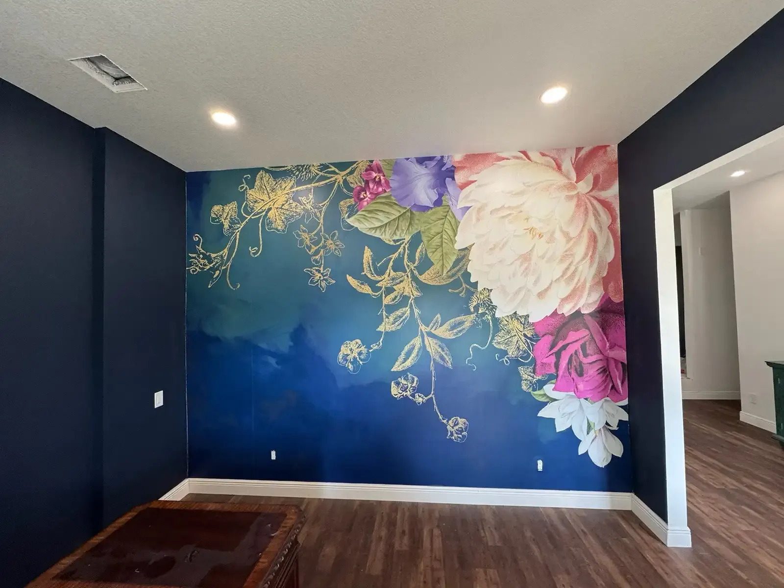 Accent wall with a large painted floral mural against a deep blue background